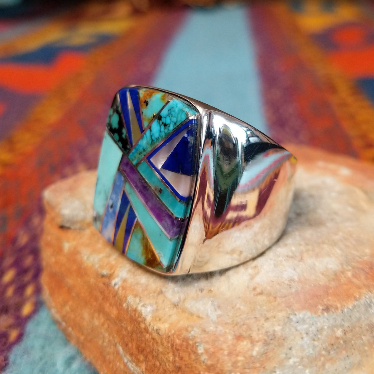 Multistone Inlay Ring by E.D. featuring a large rectangular face with geometric turquoise, blue, purple, cream, and multicolored stone inlay separated by fine silver channels; side view.
