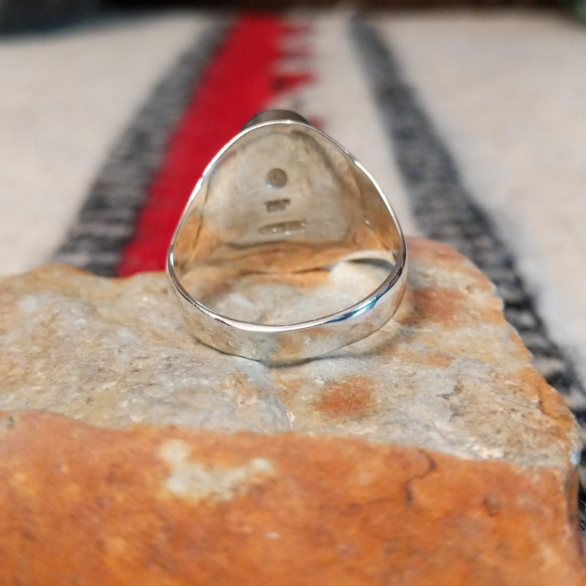 Multistone inlay ring by P.D. featuring an oval geometric design with turquoise, blue, purple, and black stones set in a polished silver band; underside view.