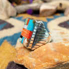 Sterling silver multistone inlay ring by Rex Abeita featuring turquoise, red coral, mother-of-pearl, black onyx, and a geometric mosaic design; side view.
