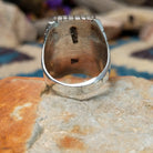 Sterling silver multistone inlay ring by Rex Abeita featuring turquoise, red coral, mother-of-pearl, black onyx, and a geometric mosaic design; underside view.