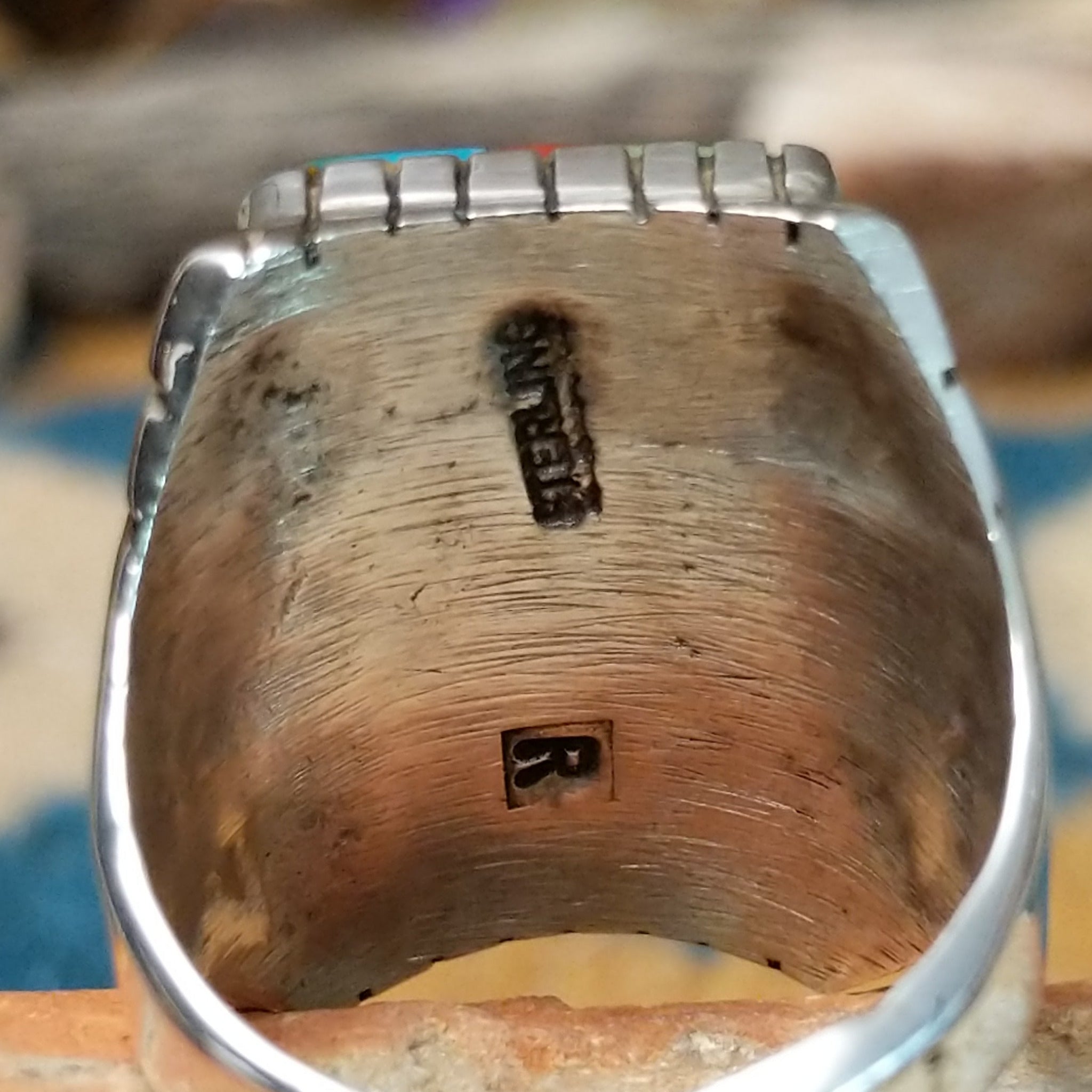 Sterling silver multistone inlay ring by Rex Abeita featuring turquoise, red coral, mother-of-pearl, black onyx, and a geometric mosaic design; artisan and Sterling Silver stamp.