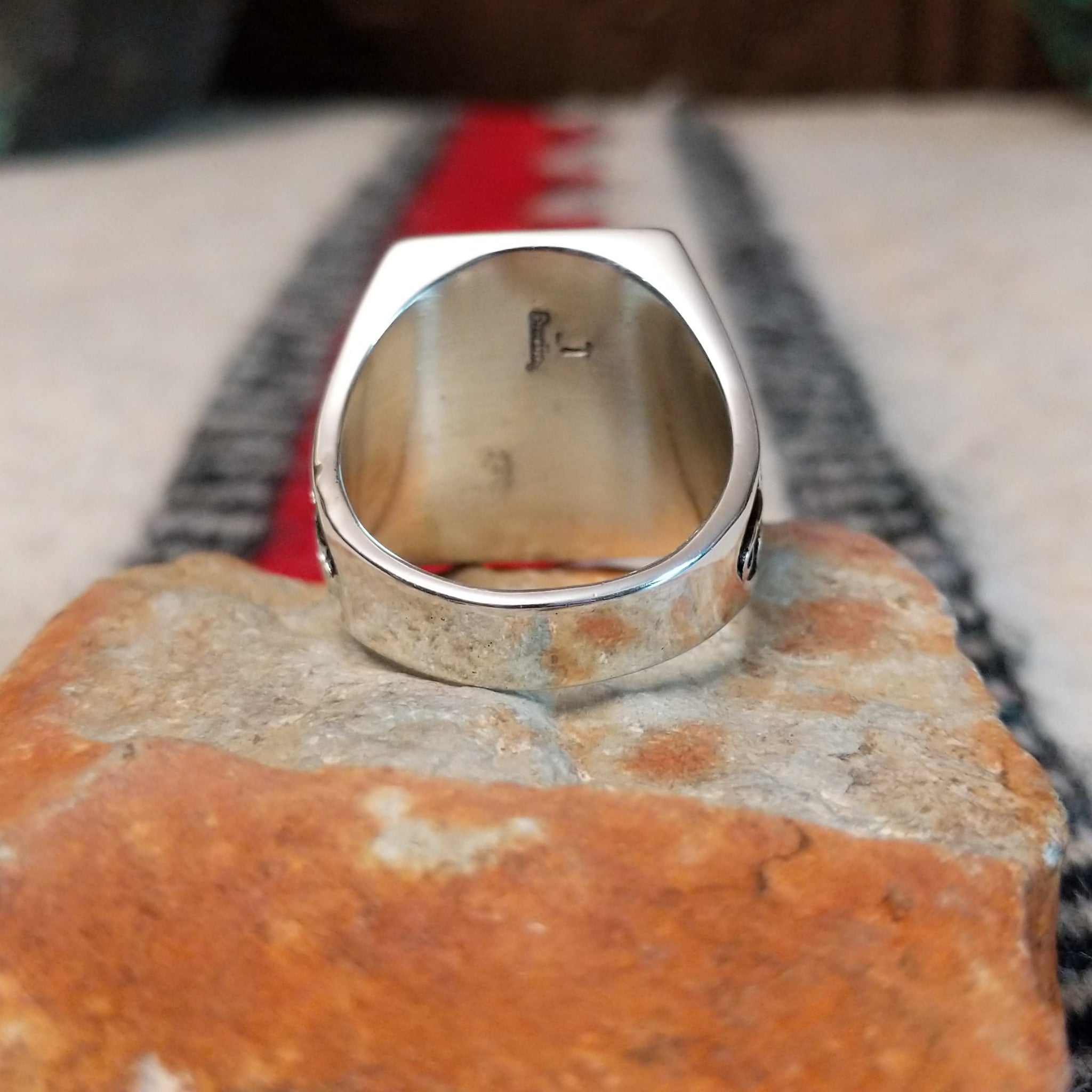 Multistone inlay ring by Terry Wood featuring a rectangular geometric design with turquoise, blue, green, orange, peach, and black stones set in silver with detailed scrollwork along the sides; underside view.