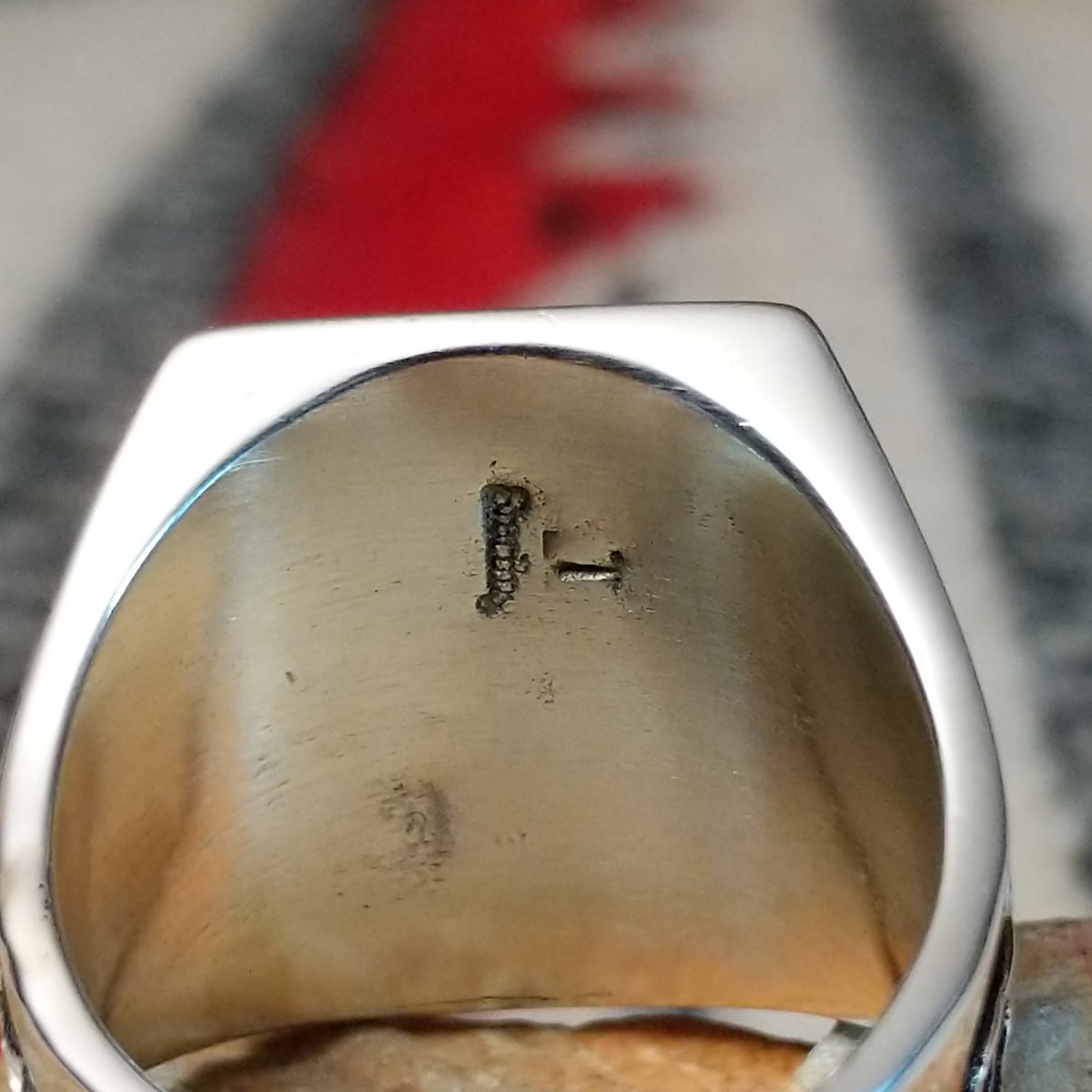 Multistone inlay ring by Terry Wood featuring a rectangular geometric design with turquoise, blue, green, orange, peach, and black stones set in silver with detailed scrollwork along the sides; artisan and Sterling Silver stamp.