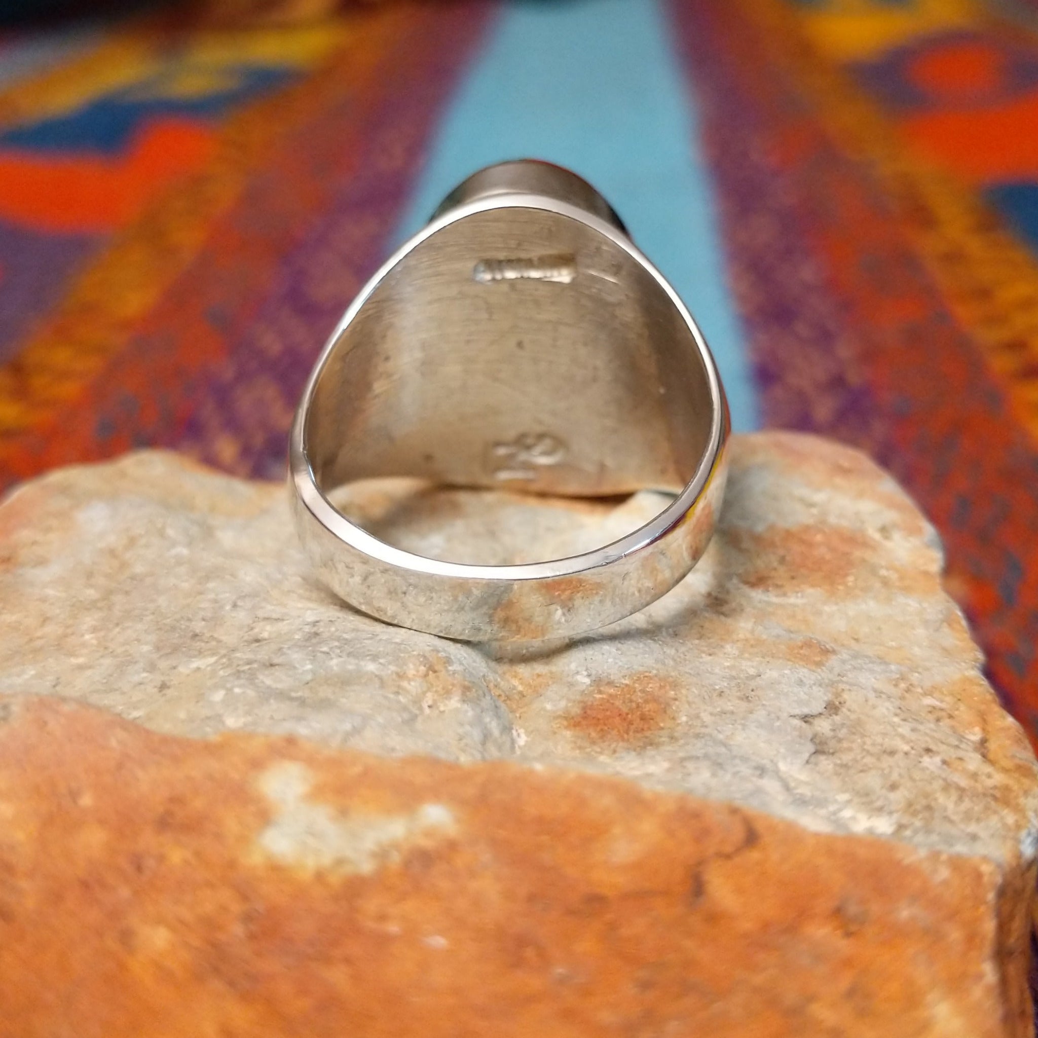 Multistone Inlay Ring by Wilbert Grey featuring an oval geometric design of orange, turquoise, and deep blue stones separated by fine silver channels in a polished silver setting; underside view.