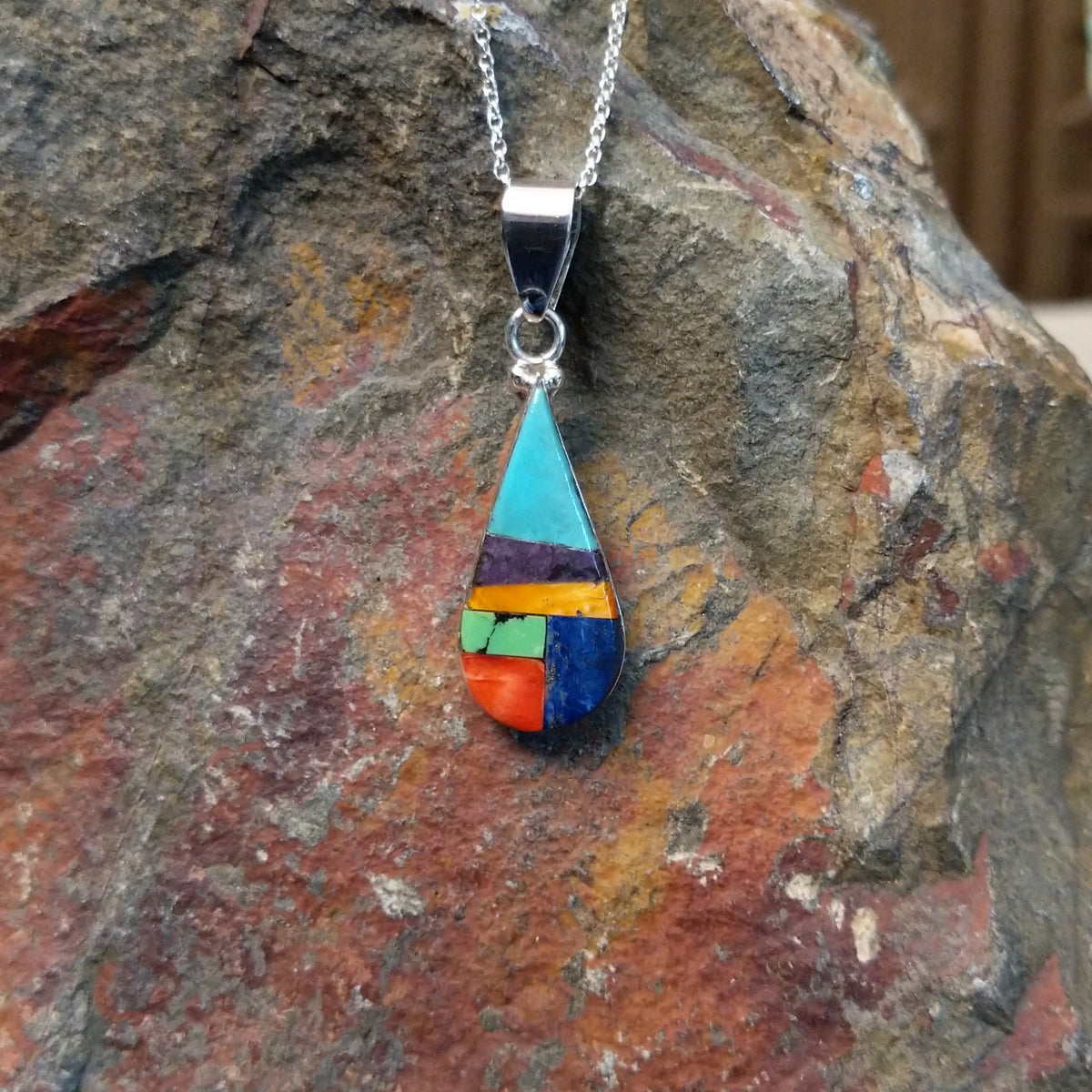 Multistone inlay teardrop pendant by P. Smith featuring turquoise, purple, orange, green, red, and blue stones arranged in a colorful geometric design.