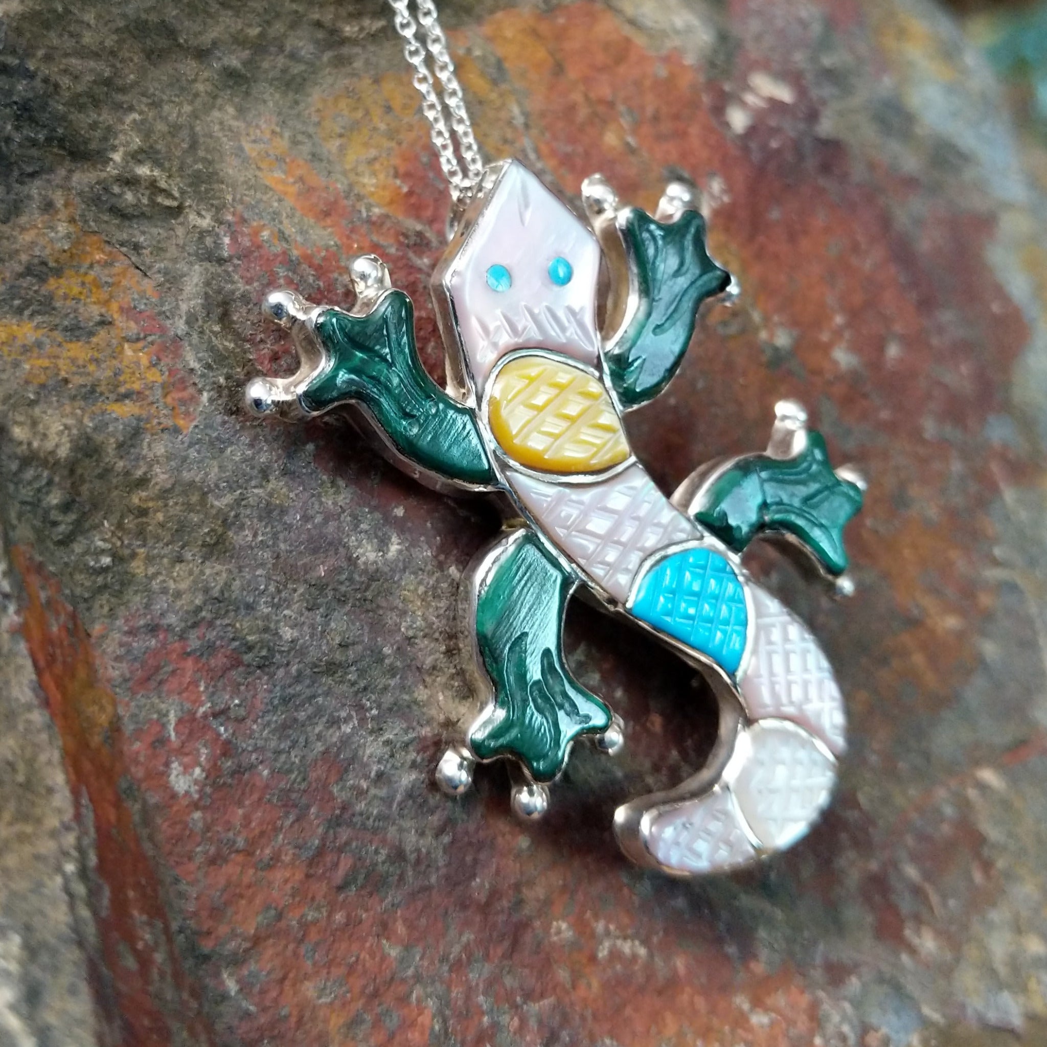 Handcrafted sterling silver multistone lizard pin and pendant by Tamara Pinto, featuring traditional Zuni inlay in a colorful lizard design; side view.