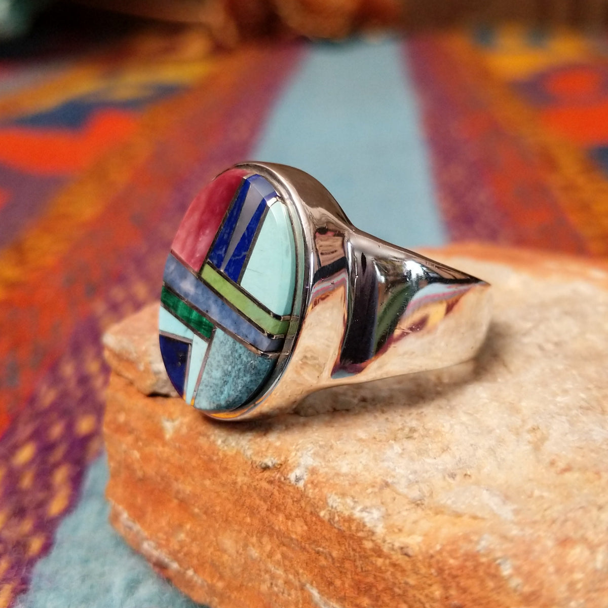 Multistone Oval Inlay Ring by E.D. featuring a geometric mosaic of stones separated by fine silver channels in a polished silver setting; side view.