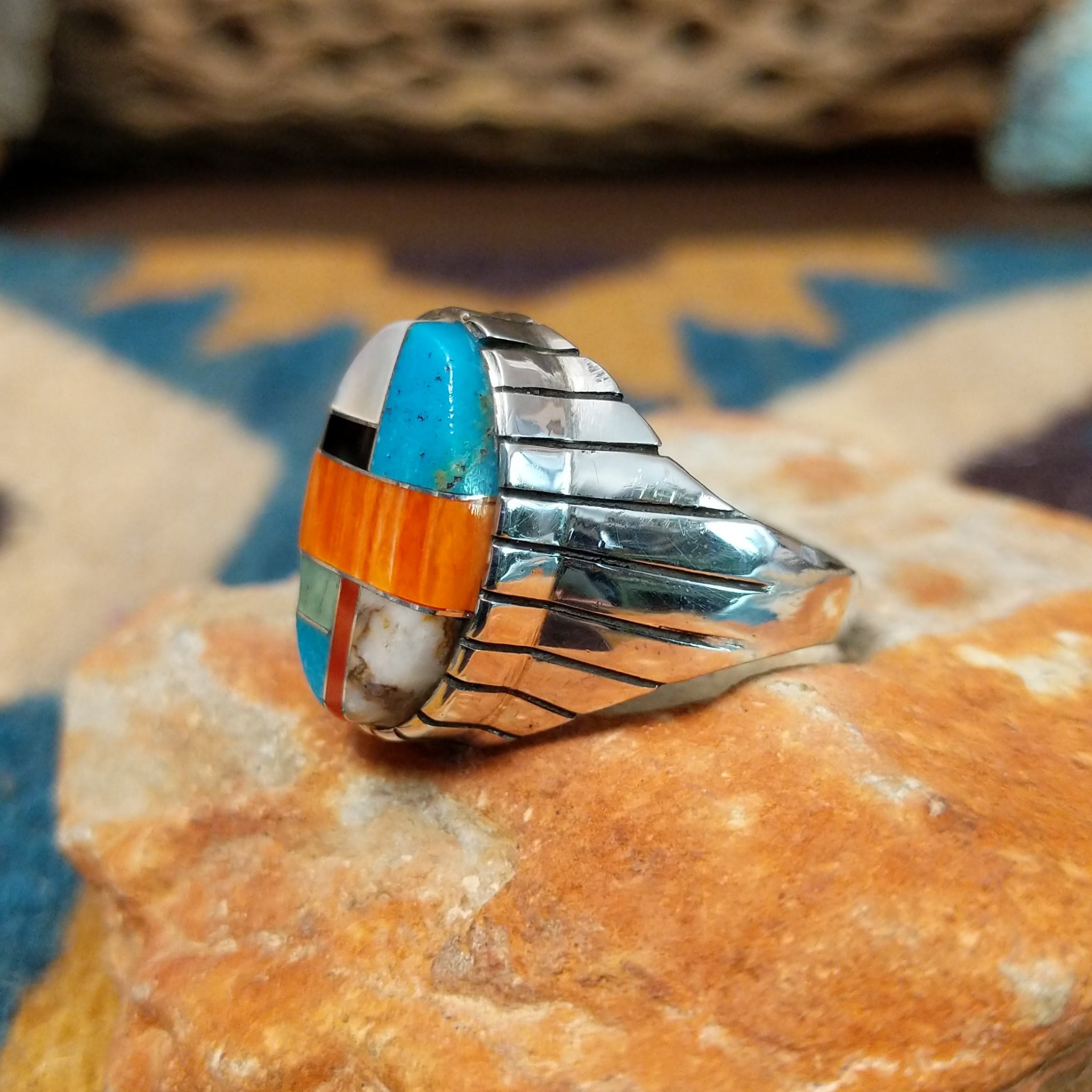 Handcrafted sterling silver oval inlay ring by Rex Abeita in a colorful geometric mosaic set in a polished silver bezel; side view.