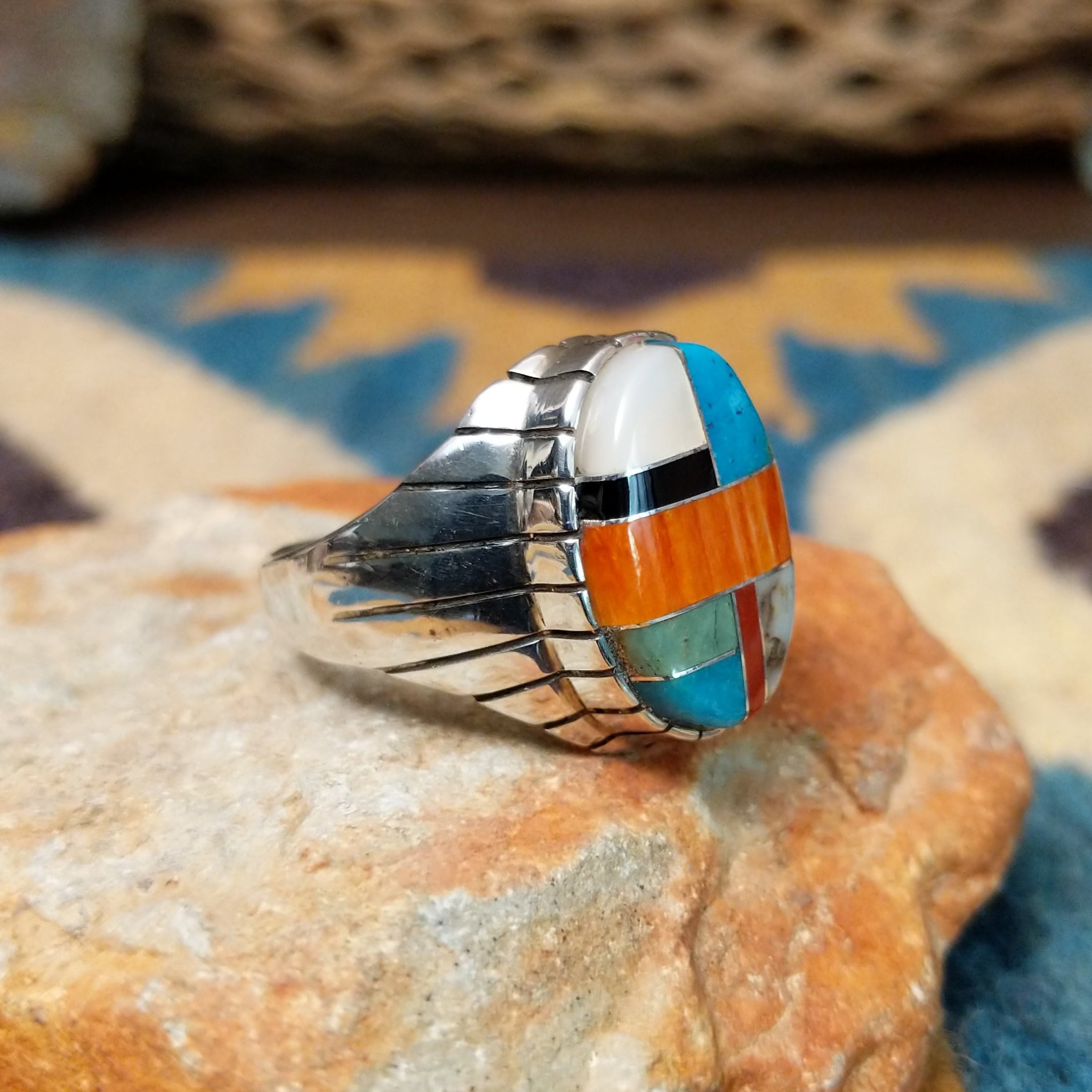 Handcrafted sterling silver oval inlay ring by Rex Abeita in a colorful geometric mosaic set in a polished silver bezel; side view.