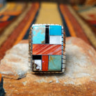 This vibrant Multistone Rectangle Inlay Ring by Wilbert Grey features a geometric arrangement of turquoise, coral, black, and white stone inlays set in a rectangular silver face with a detailed band.