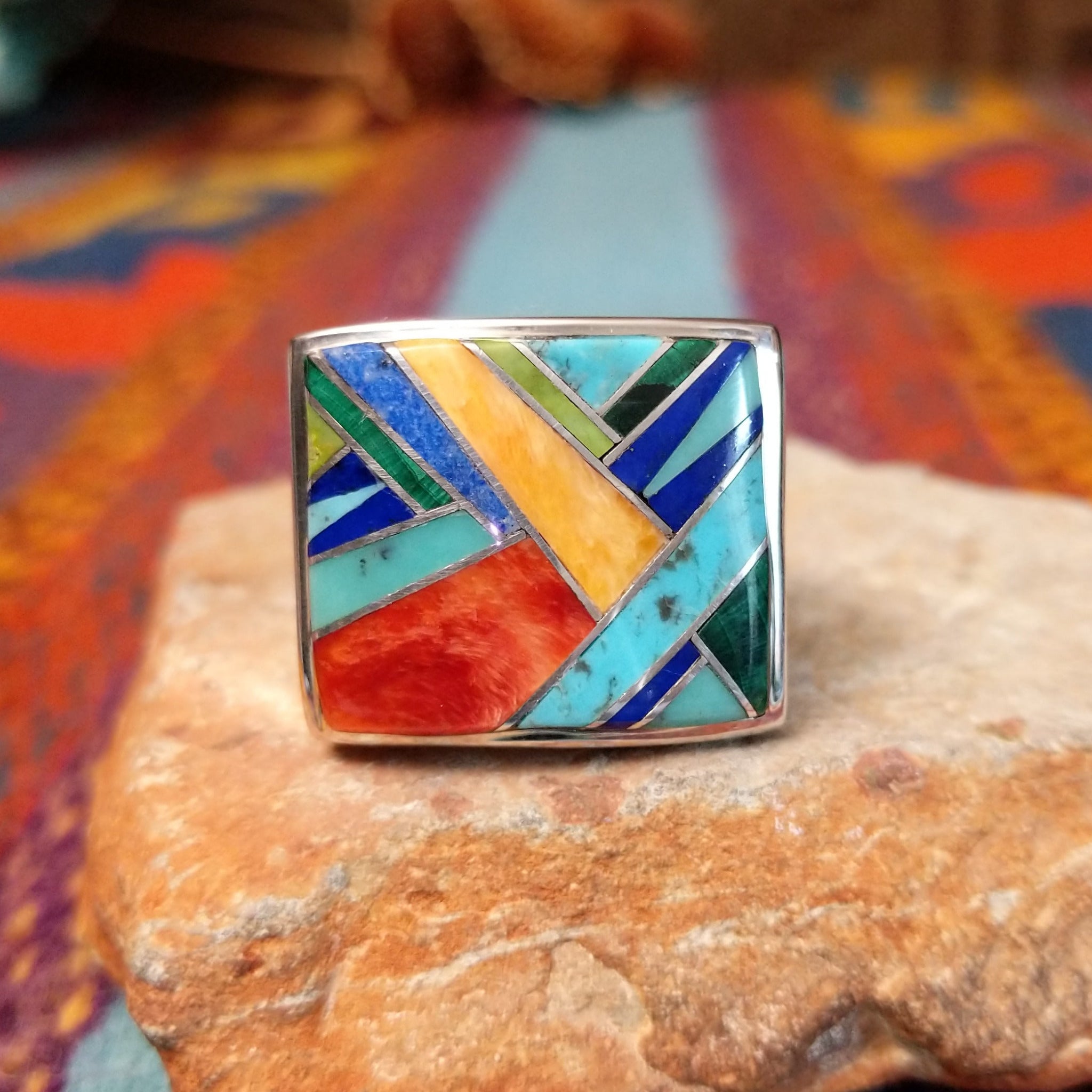 Multistone Square Inlay Ring by O.J. featuring colorful geometric turquoise, blue, red, yellow, and green stone inlay separated by Sterling Silver channels on a broad square face.