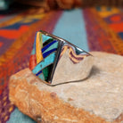 Multistone Square Inlay Ring by O.J. featuring colorful geometric turquoise, blue, red, yellow, and green stone inlay separated by Sterling Silver channels on a broad square face; side view.