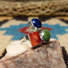 Multistone trio ring by Ann Curley, featuring blue lapis, green turquoise, and red spiny oyster shell set in a handcrafted sterling silver ring with a contemporary design.  Side view.