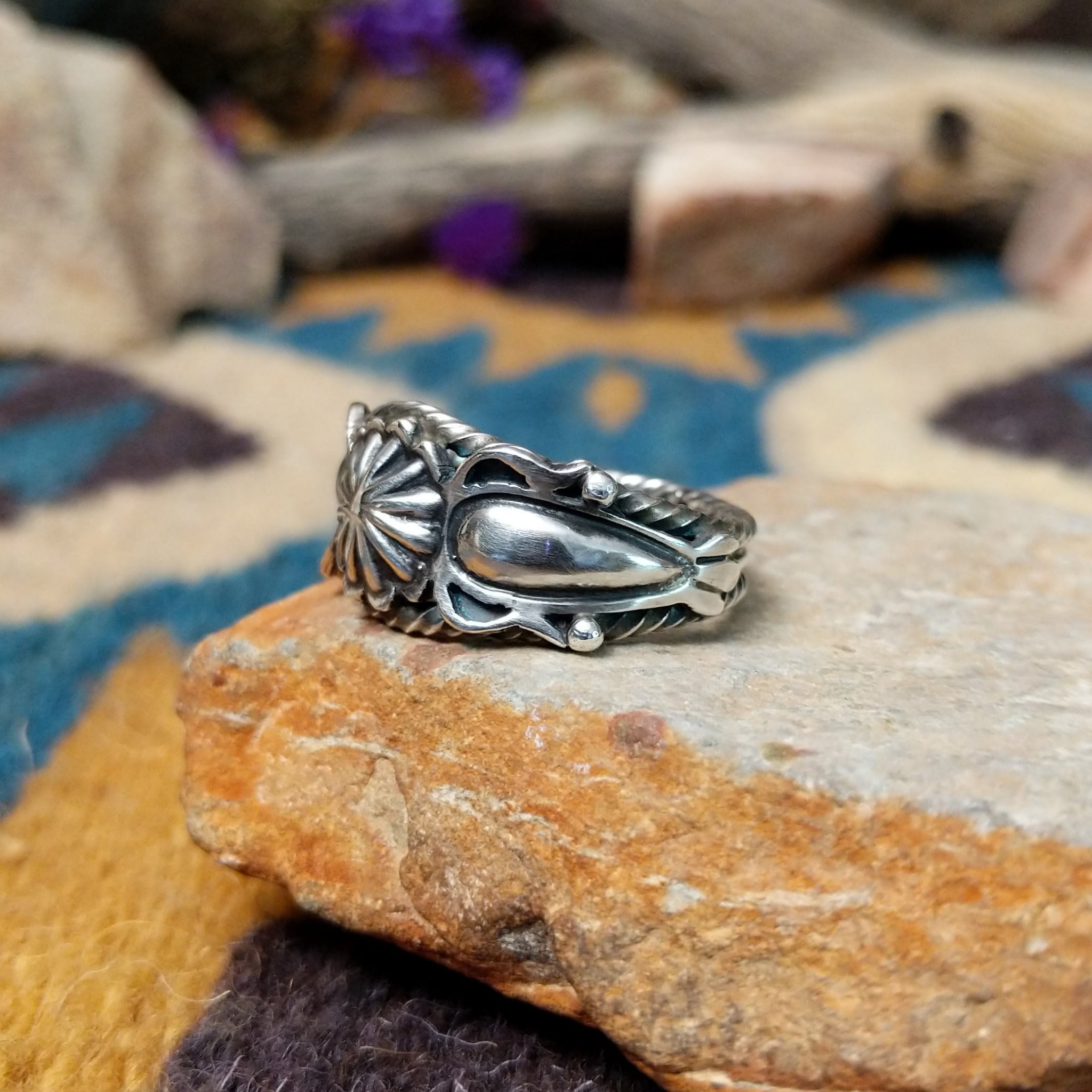 Navajo sterling silver ring with a hand-stamped floral design and polished silver accents; side view.