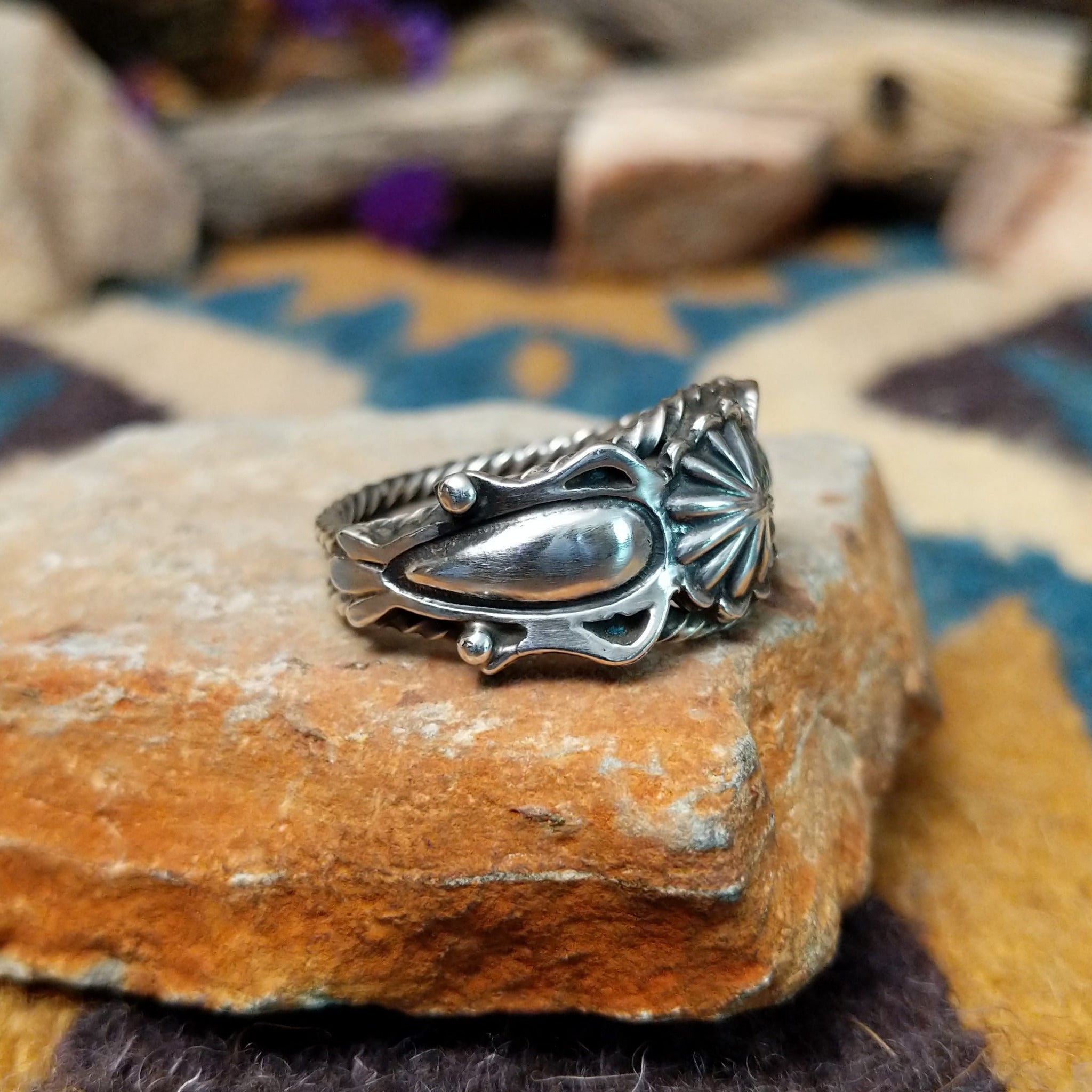 Navajo sterling silver ring with a hand-stamped floral design and polished silver accents; side view.