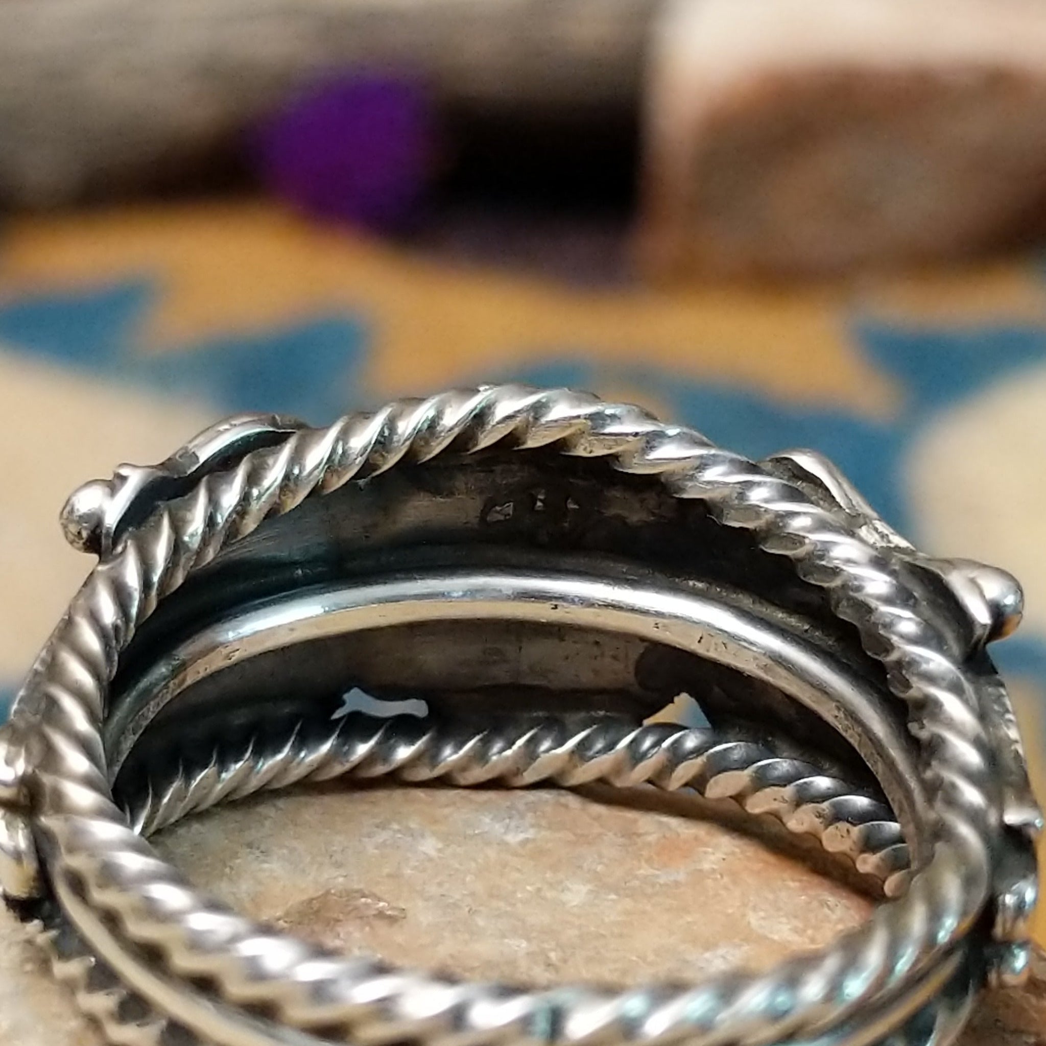 Navajo sterling silver ring with a hand-stamped floral design and polished silver accents; artisan stamp.