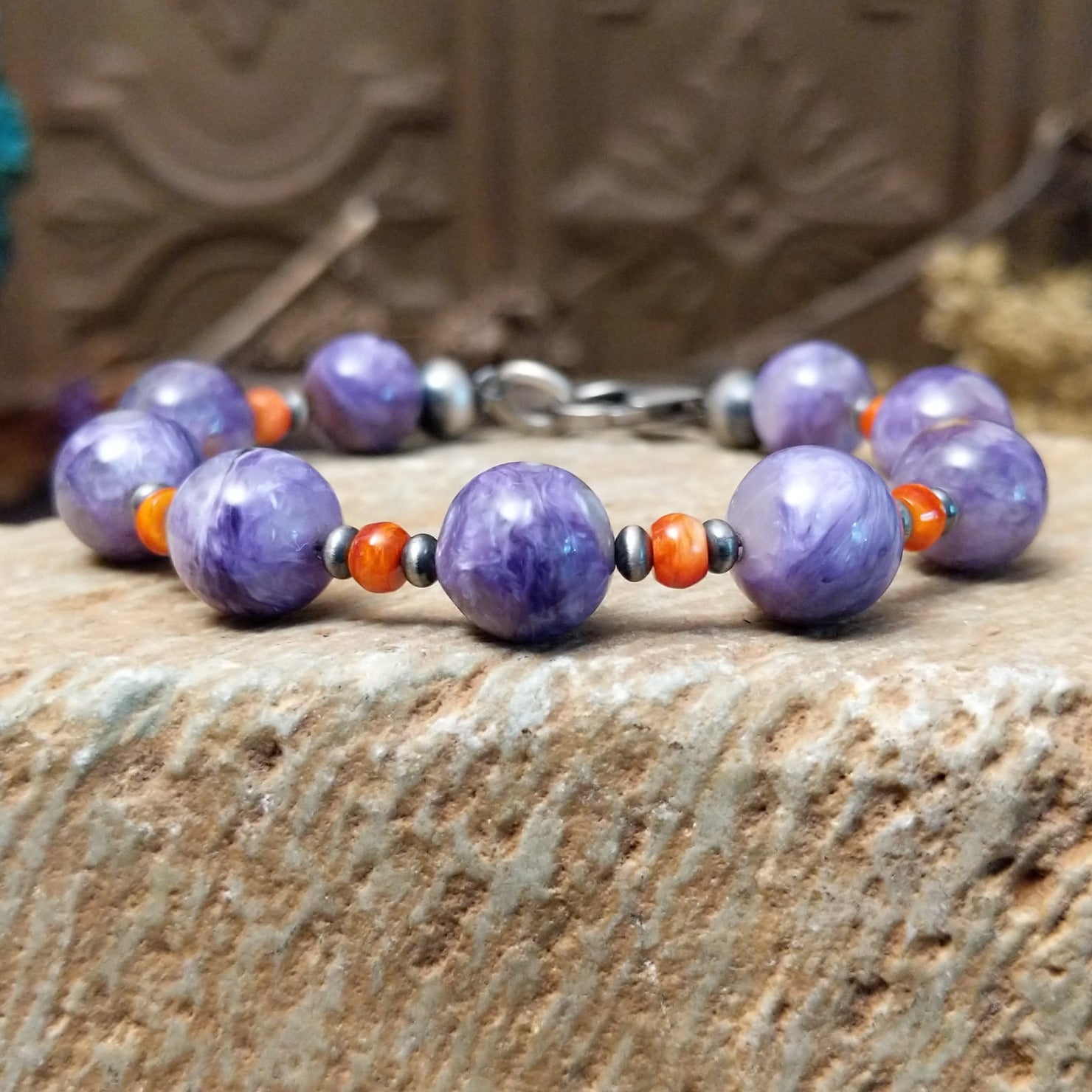 Beaded charoite bracelet with accents of sterling silver and orange spiny oyster shell.