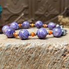 Beaded charoite bracelet with accents of sterling silver and orange spiny oyster shell.