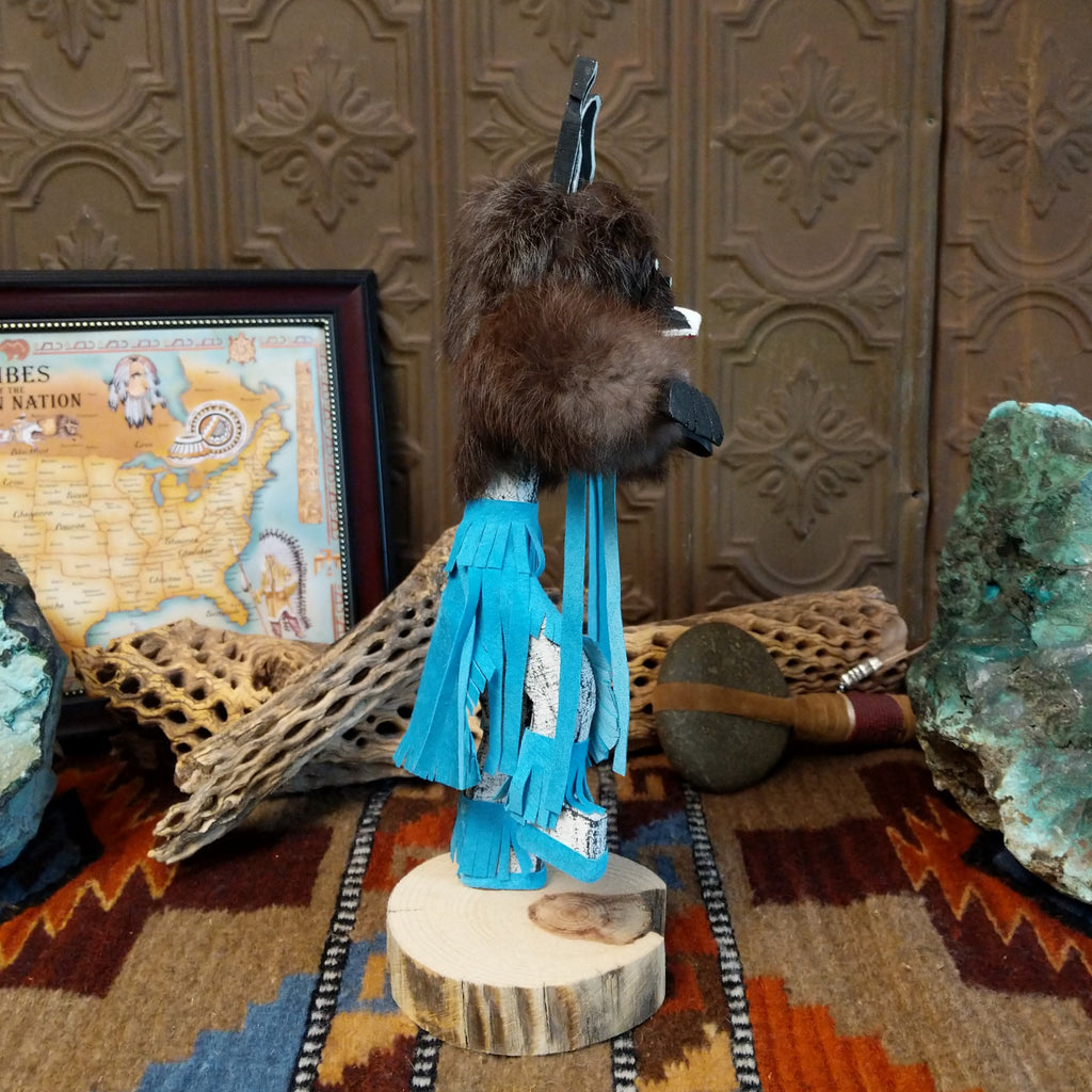 Wood carved into a bear kachina with fur body, blue suede clothing, and paint.