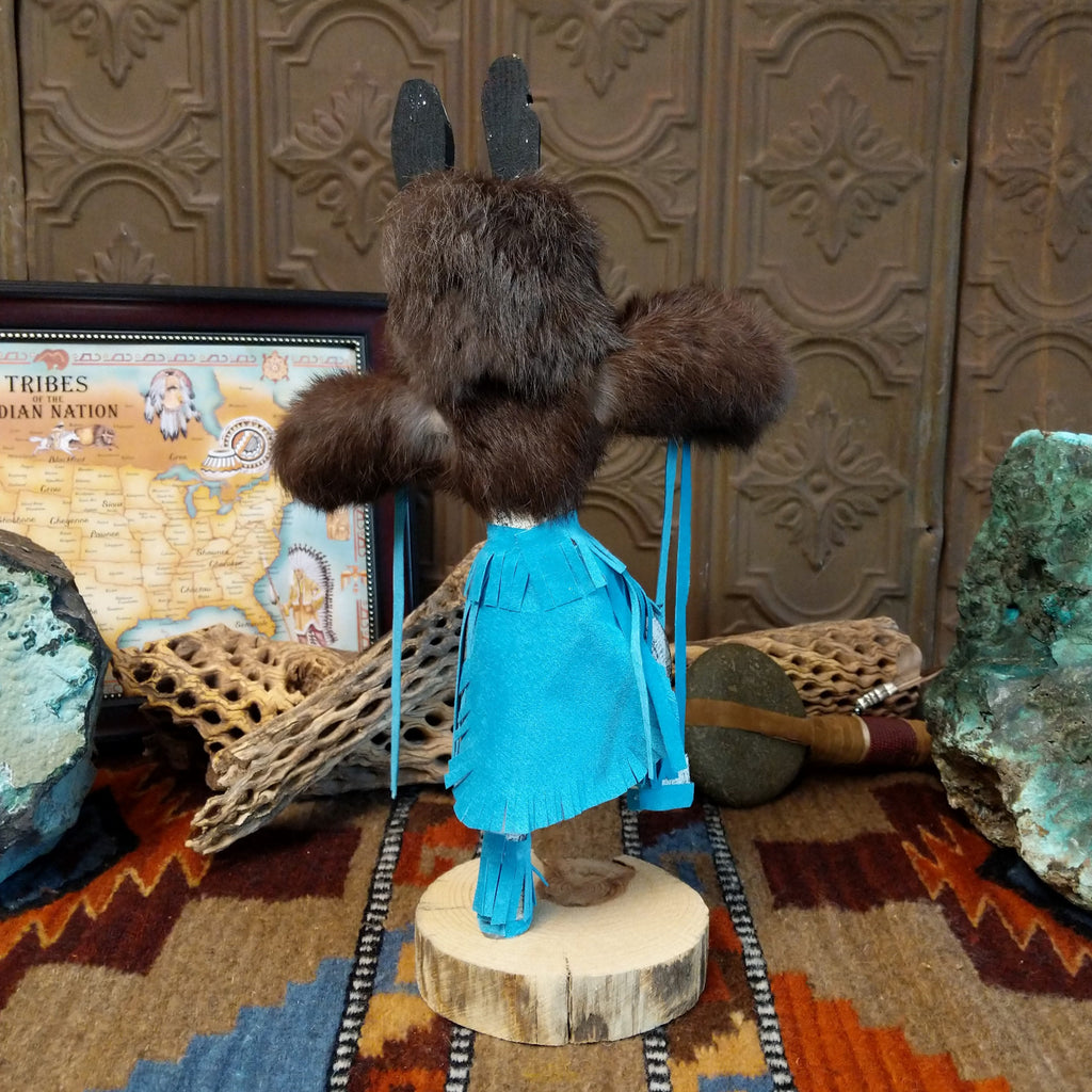 Wood carved into a bear kachina with fur body, blue suede clothing, and paint.