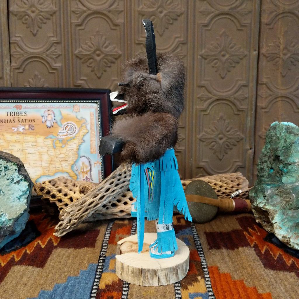Wood carved into a bear kachina with fur body, blue suede clothing, and paint.