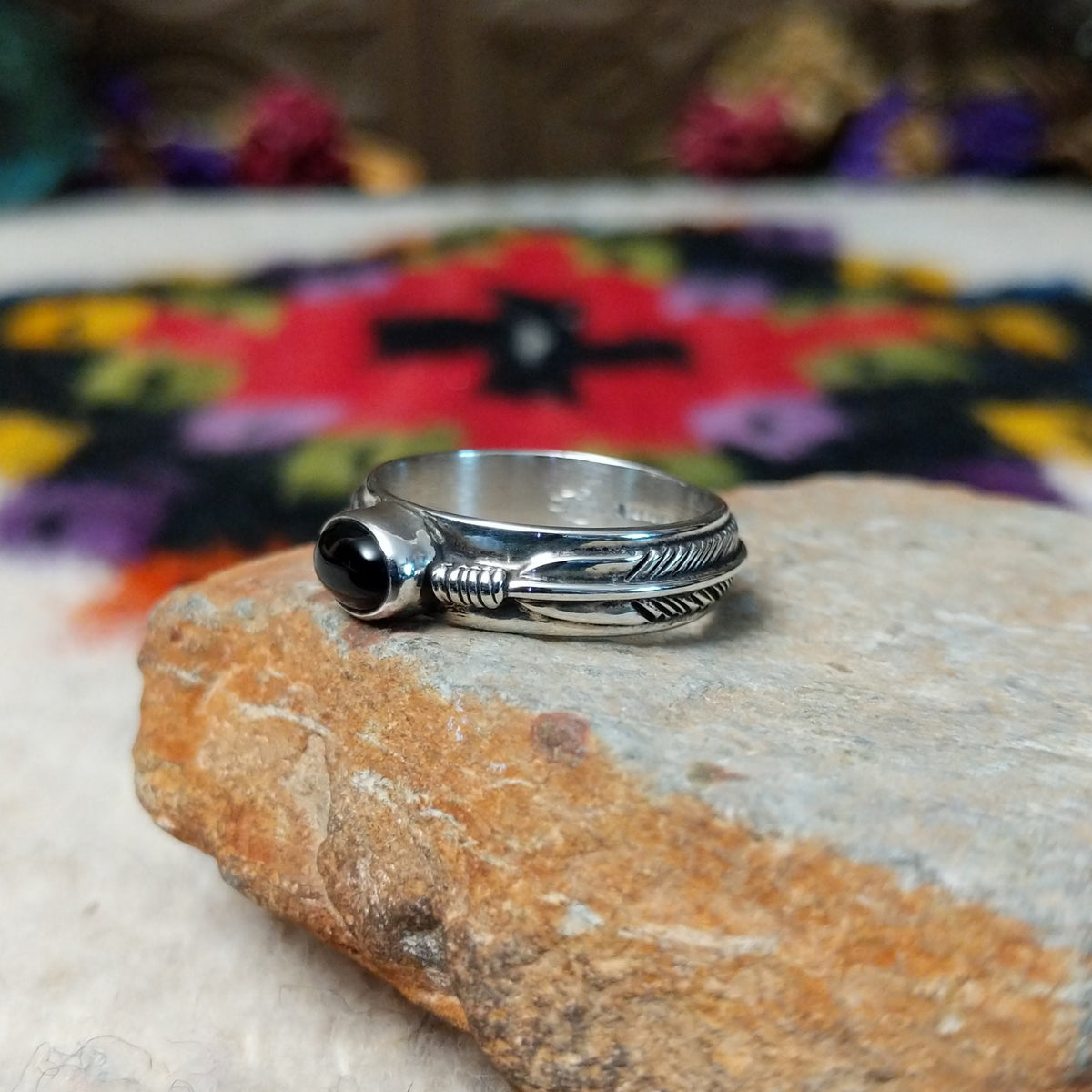 Refined Navajo Black Onyx Feather Ring featuring a polished oval black onyx stone set in sterling silver with detailed feather-inspired silverwork along the band; side view.