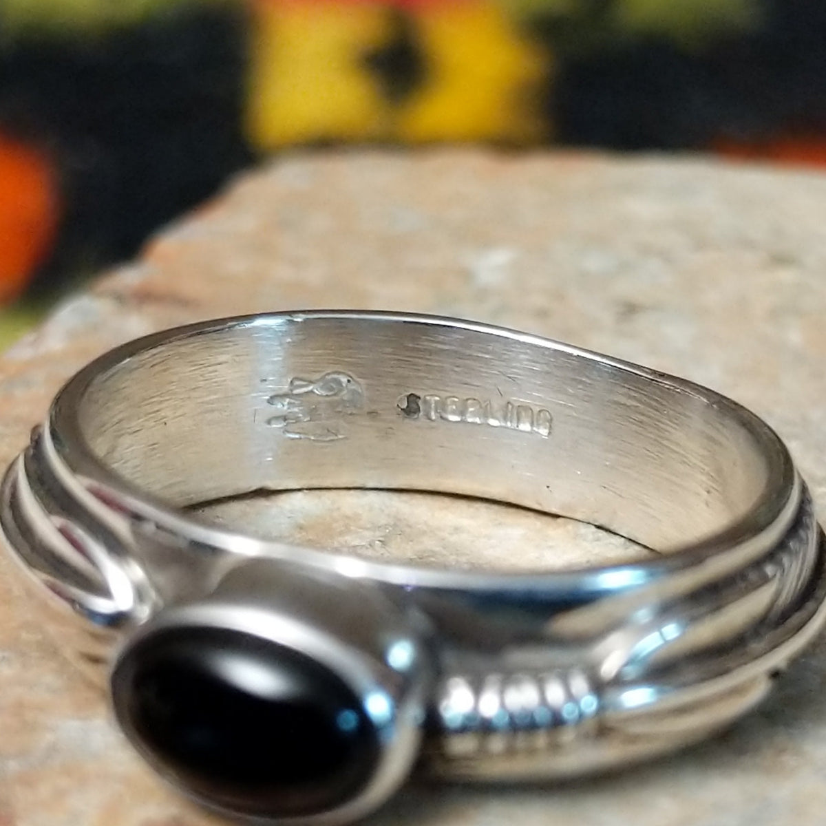 Refined Navajo Black Onyx Feather Ring featuring a polished oval black onyx stone set in sterling silver with detailed feather-inspired silverwork along the band; artisan and Sterling Silver stamp.