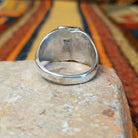 Navajo Black Onyx Ring featuring a polished rectangular black onyx gemstone in a sawtooth silver bezel, with a wide silver band accented by stamped fan-shaped designs on both sides; underside view.