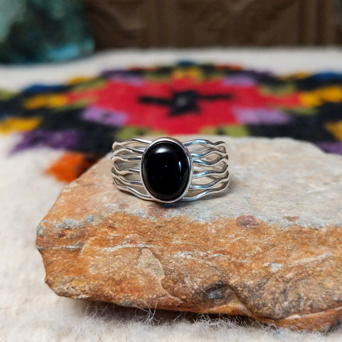 Navajo silver ring with polished black onyx and a multi-strand wavy band.