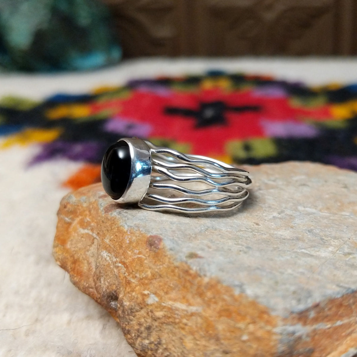 Navajo silver ring with polished black onyx and a multi-strand wavy band.