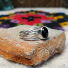 Navajo silver ring with polished black onyx and a multi-strand wavy band.