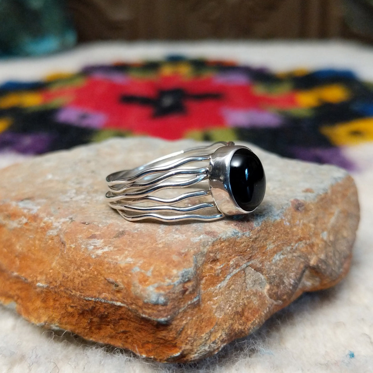 Navajo silver ring with polished black onyx and a multi-strand wavy band.