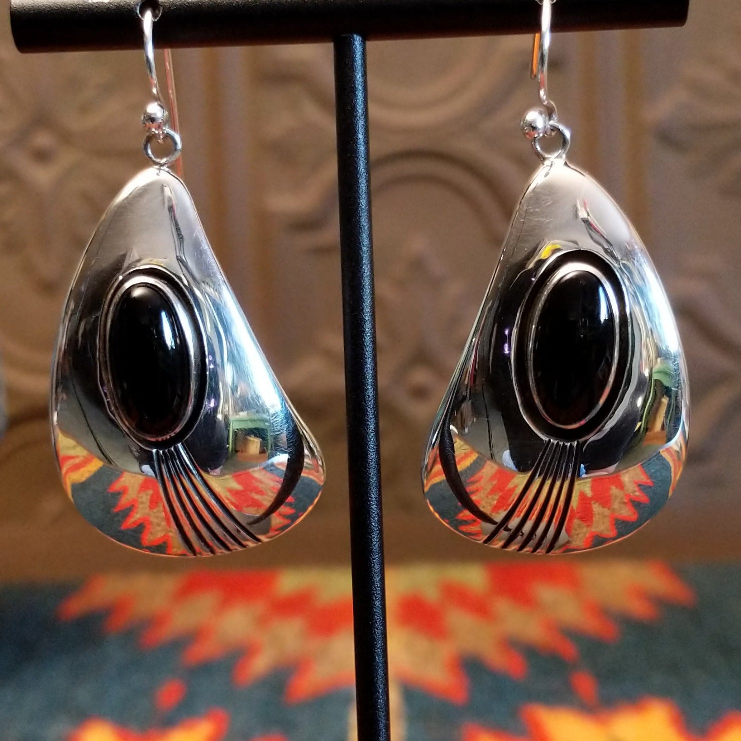 Sterling silver earrings with black onyx set in oval bezels, framed by the wavey silver settings and lined stamping.