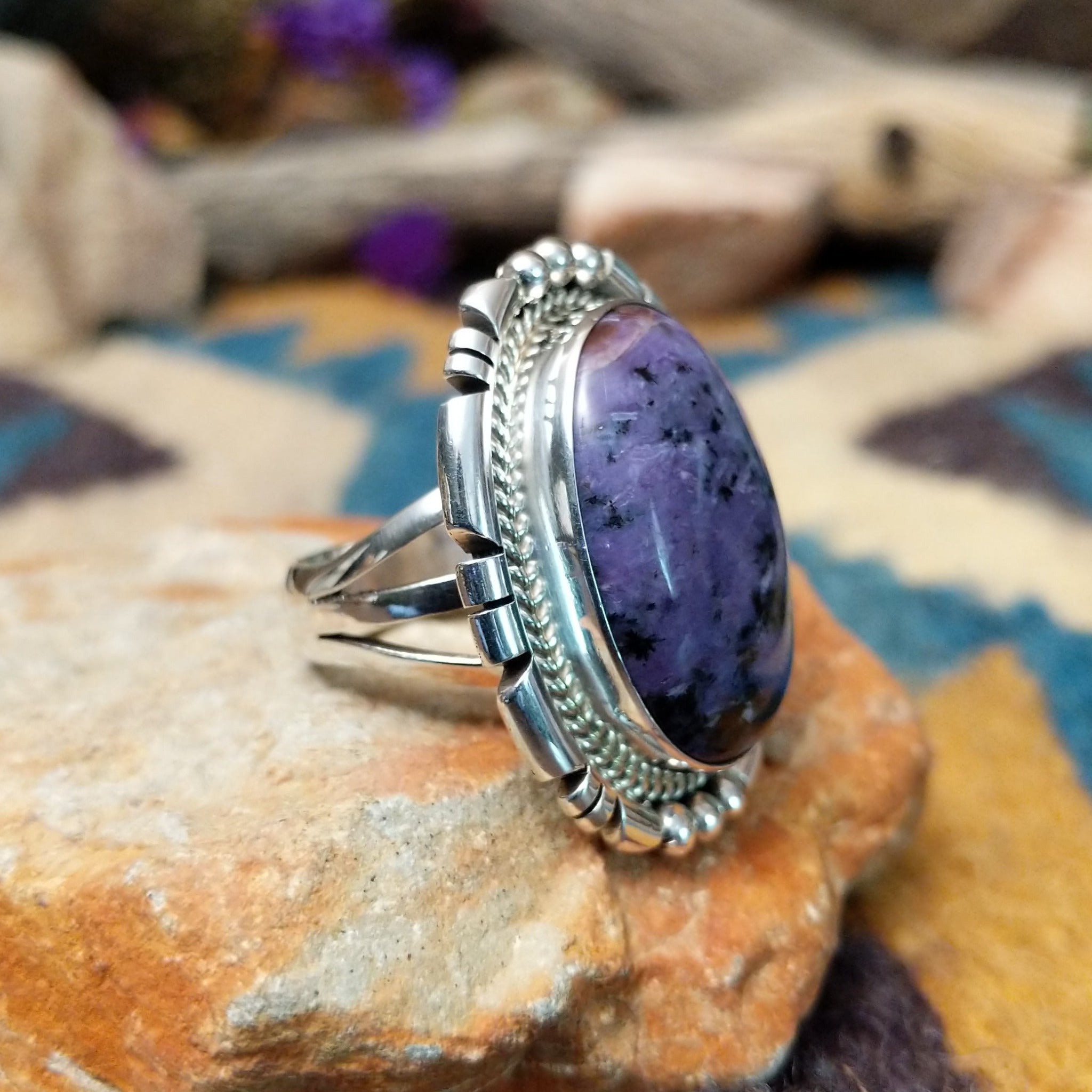 Navajo sterling silver ring with an oval Charoite stone in shades of purple with natural black inclusions; side view.