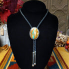 A braided bolo tie necklace displayed on a black velvet mannequin bust. The necklace features a round Boulder Turquoise cabochon pendant with a Sterling Silver bezel, and two dangling silver barbell beads on a braided cord.