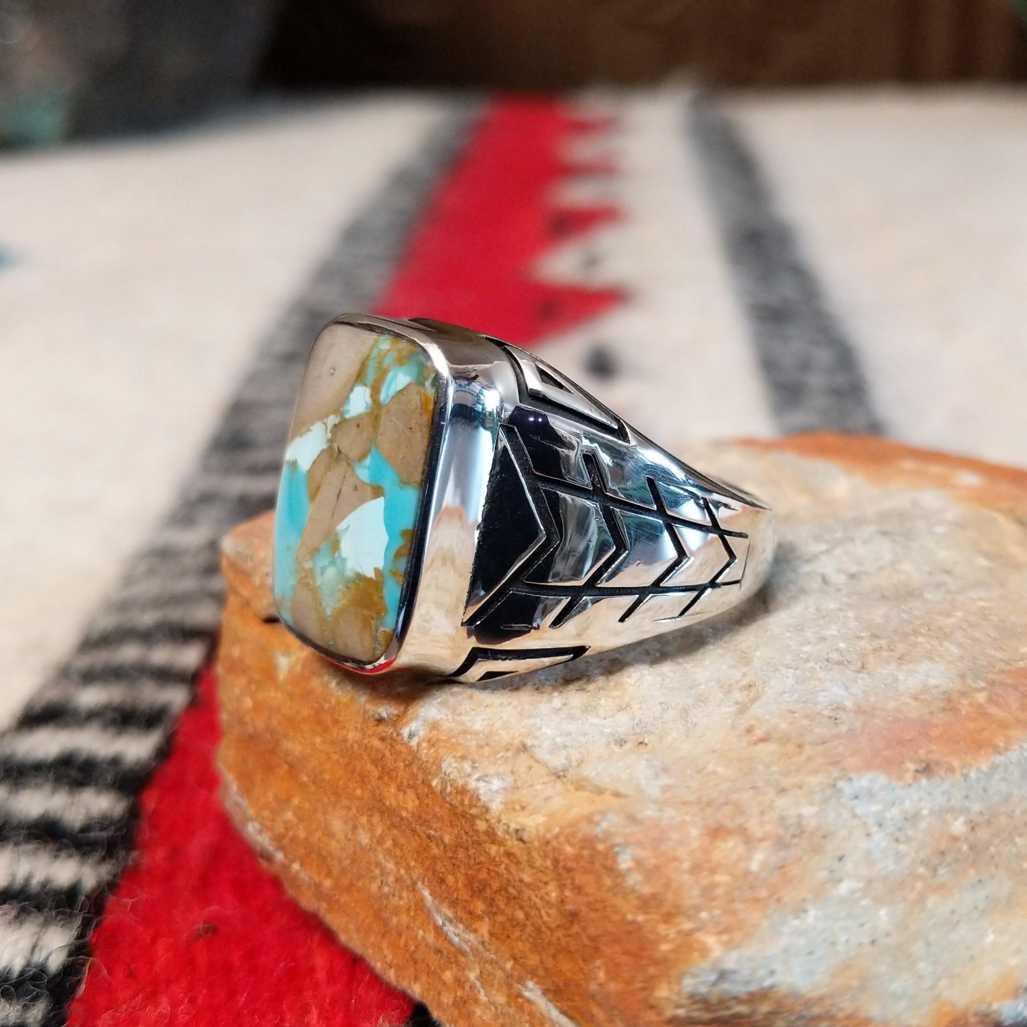 Navajo Boulder Turquoise Ring by E. featuring a rectangular turquoise stone with prominent natural brown host rock, set in a polished silver band with geometric stamped accents; side view.