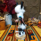 Side view of the Navajo Buffalo Dancer Kachina doll with black horns, thick white fur, black-and-white painted details, and blue shoulder accents.
