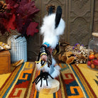 Side view of the Navajo Buffalo Dancer Kachina doll with black horns, thick white fur, black-and-white painted details, and blue shoulder accents.