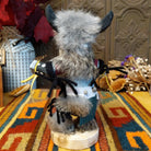 This distinctive Navajo Buffalo Kachina by Debbie James features a hand-painted wooden figure with black buffalo horns, gray fur headdress, black-and-white painted details, natural feathers, leather ties, and a wooden display base; back view.