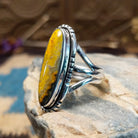 Sterling silver ring with bumblebee jasper set in a capsule bezel, framed by incised designs.