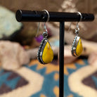 Handcrafted Navajo sterling silver teardrop earrings featuring vibrant Bumblebee Jasper cabochons with golden-yellow tones, natural earthy inclusions, and twisted rope border detailing; side view.