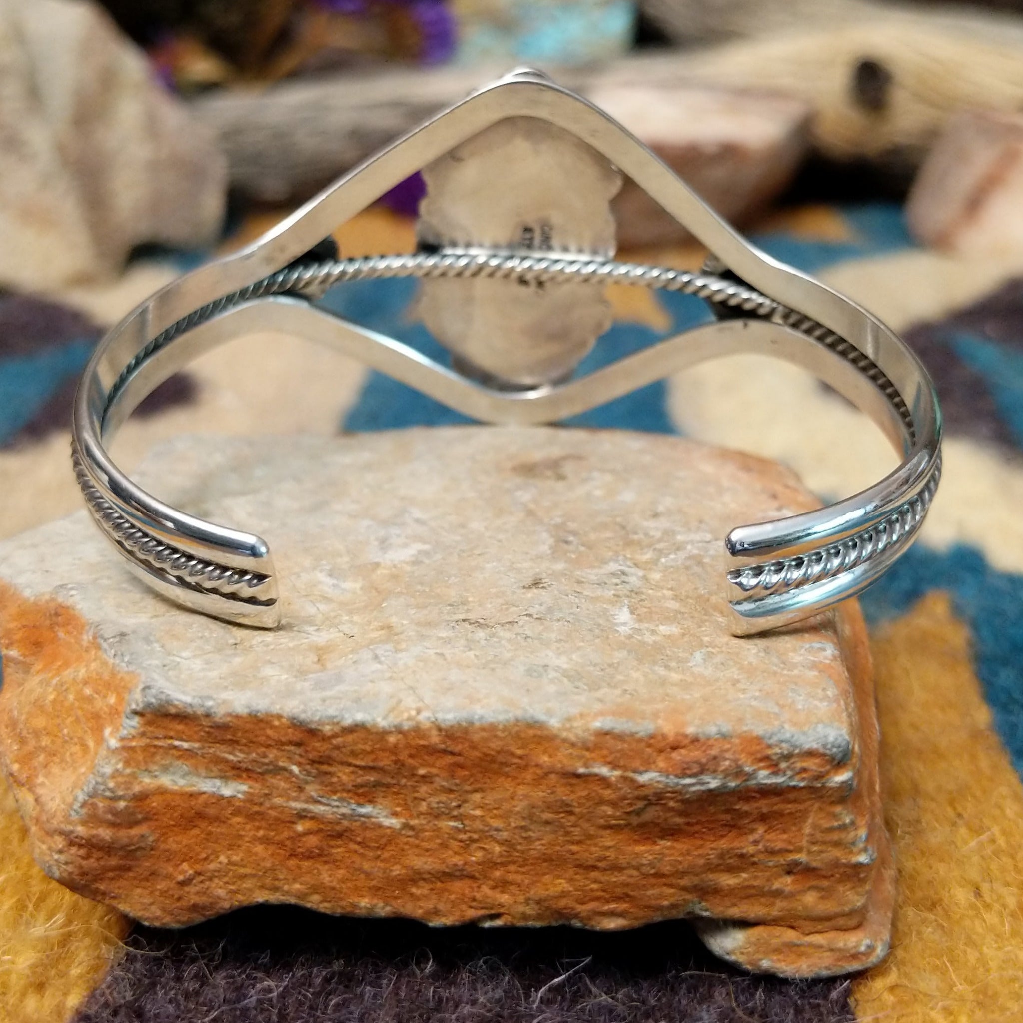 Handcrafted Navajo sterling silver cuff featuring an oval Carico Lake turquoise cabochon surrounded by ornate silver beadwork, scroll accents, and an open diamond-shaped frame; underside view.