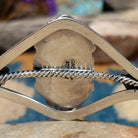 Handcrafted Navajo sterling silver cuff featuring an oval Carico Lake turquoise cabochon surrounded by ornate silver beadwork, scroll accents, and an open diamond-shaped frame; artisan and Sterling Silver stamp.