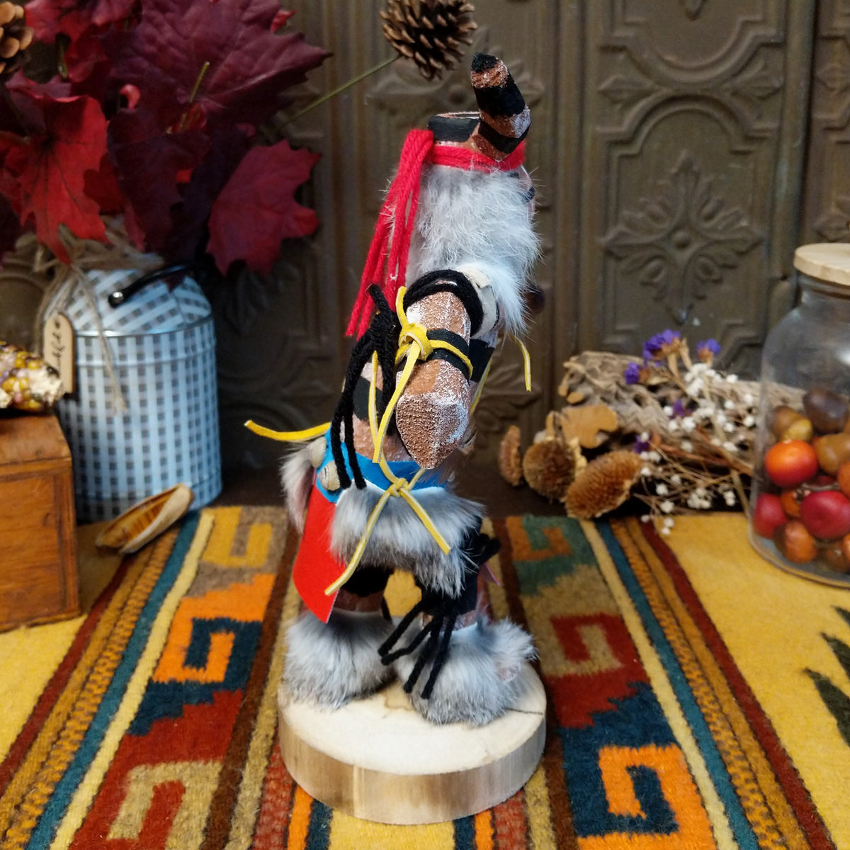 Side view of the Navajo Ogre Kachina doll with gray fur-covered face, black horns with turquoise markings, open red mouth, pointed teeth, and green fabric apron.