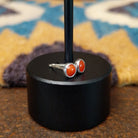 Handcrafted Navajo sterling silver stud earrings featuring round coral accents in polished silver; side view.