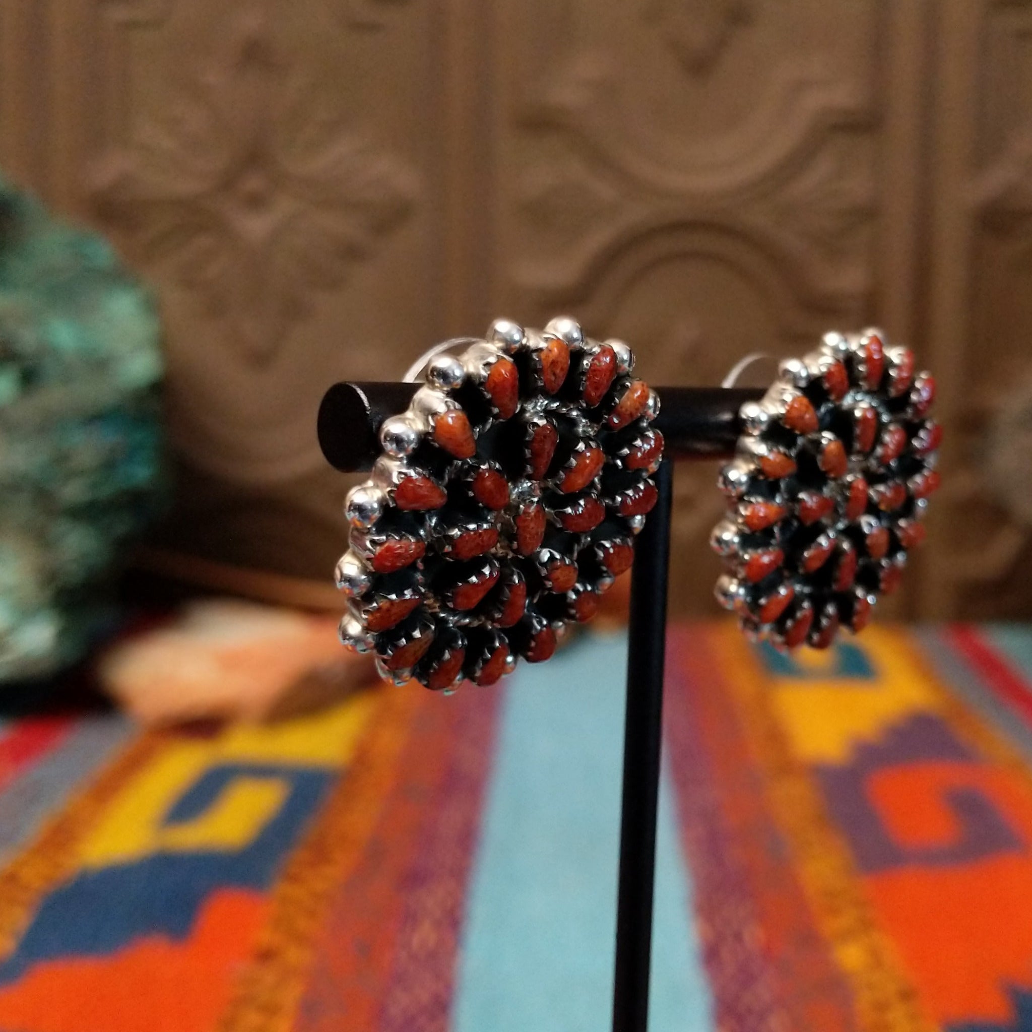 Navajo sterling silver matching earrings by B.Y., featuring numerous red-orange coral stones arranged in floral clusters.