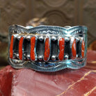 Sterling silver cuff with coral set in a septet of bezels, framed by ornate stamping and silverwork.
