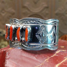 Sterling silver cuff with coral set in a septet of bezels, framed by ornate stamping and silverwork.