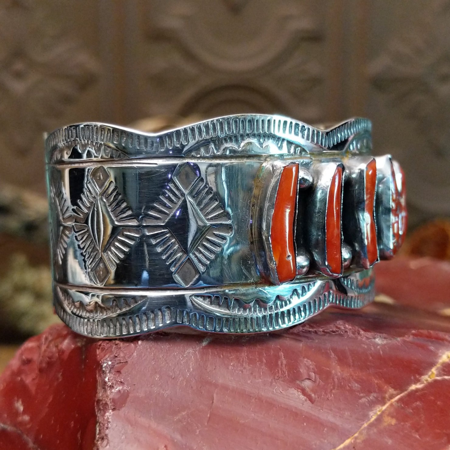 Sterling silver cuff with coral set in a septet of bezels, framed by ornate stamping and silverwork.
