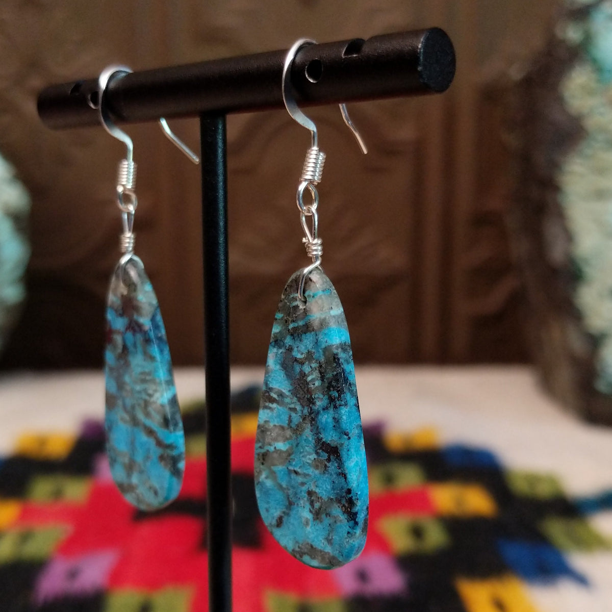 Navajo Dark Matrix Slab Turquoise Earrings featuring elongated blue turquoise stones with bold black and gray matrix patterns, suspended from silver hooks; side view.